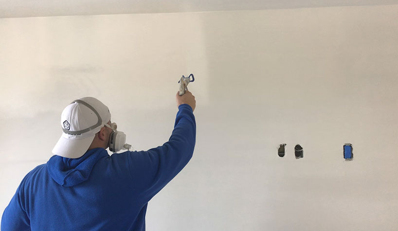 Jonah Lupton, founder/CEO of SoundGuard, sprays the soundproofing paint.